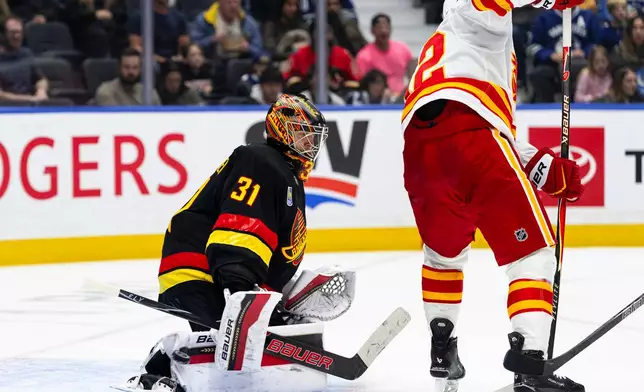 Vancouver Canucks goalie Leevi Merilainen (31) stops the puck as Calgary Flames' Matvei Gridin (92) screens him during the second period of an NHL hockey game in Vancouver, British Columbia, Saturday, Oct. 3, 2026. (Jacob Mallari/The Canadian Press via AP)