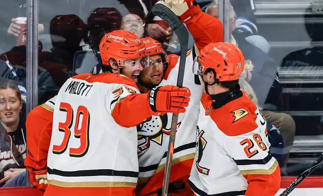 Anaheim Ducks' Jeff Malott (39), Tim Washe (42) and Judd Caulfield (28) celebrate after Washe's goal against the Winnipeg Jets during the second period of an NHL hockey game in Winnipeg, Manitoba, Friday, Oct. 9, 2026. (John Woods/The Canadian Press via AP)
