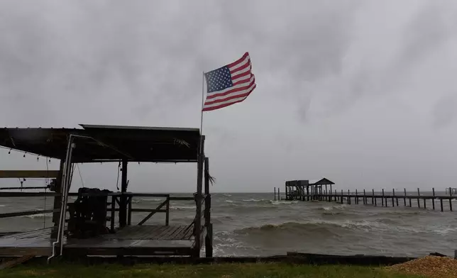An American flag flaps in the wind generated by the effects of Isaias on an empty beach on Friday, Oct. 9, loom overhead on Friday, Oct. 9, 2026, in Mon Louis Island, Ala. (AP Photo/Octavio Jones)