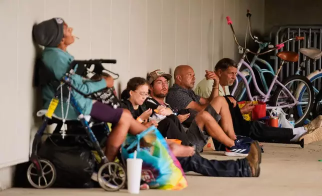 People sit outside an evacuation shelter as Hurricane Isaias approaches Pensacola, Fla., Friday, Oct. 9, 2026. (AP Photo/Gerald Herbert)