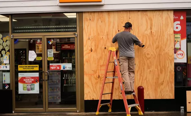 Jason Coffey boards up a convenience store at a gas station as Hurricane Isaias approaches Pensacola Beach, Fla., Friday, Oct. 9, 2026. (AP Photo/Gerald Herbert)