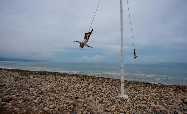 The Flying Men of Papantla perform the "Danza de los Voladores" on the beach as Hurricane Simon approaches Puerto Vallarta, Mexico, Saturday, Oct. 10, 2026. (AP Photo/Fernando Llano)