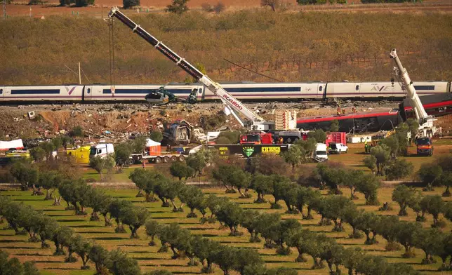 Cranes lift wrecked train carriages as rescuers search for victims following a collision between two trains in Urda, Spain, Thursday, Oct. 29, 2026. (AP Photo/Manu Fernandez)