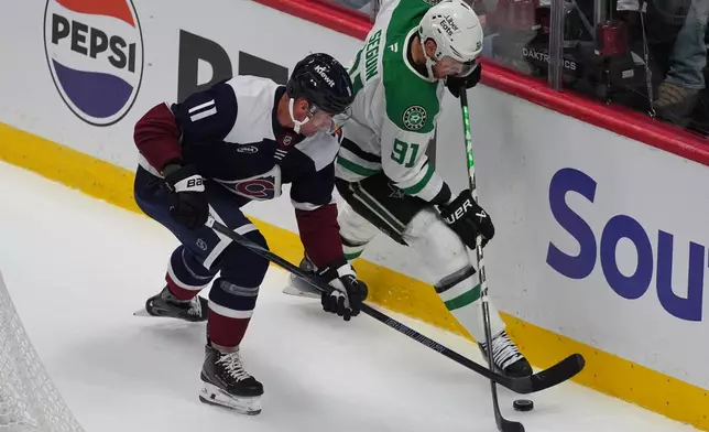 Colorado Avalanche center Brock Nelson, left, fights for control of the puck with Dallas Stars center Tyler Seguin in the first period of an NHL hockey game Wednesday, Oct. 14, 2026, in Denver. (AP Photo/David Zalubowski)