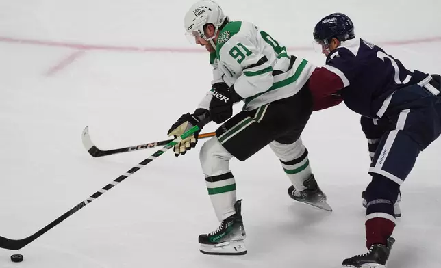 Dallas Stars center Tyler Seguin, left, drives past Colorado Avalanche defenseman Brett Kulak in the second period of an NHL hockey game Wednesday, Oct. 14, 2026, in Denver. (AP Photo/David Zalubowski)