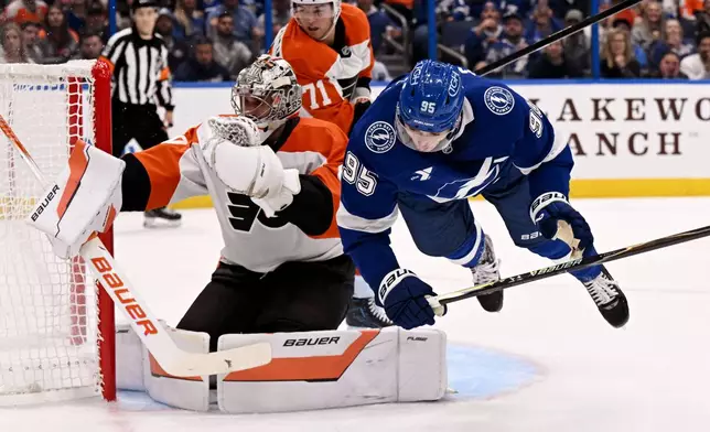 Tampa Bay Lightning right wing Ilya Mikheyev (95) is tripped as he collides with Philadelphia Flyers goaltender Dan Vladar, front left, during the second period of an NHL hockey game Monday, Oct. 5, 2026, in Tampa, Fla. (AP Photo/Jason Behnken)
