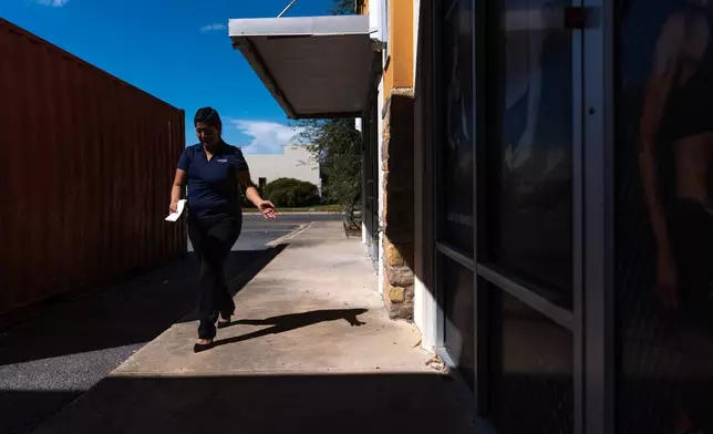 Cindy Banda walks back to her car after leaving flyers advertising Spectrum internet services at local businesses, Sept. 14, 2026, in McAllen, Texas. (AP Photo/Julia Demaree Nikhinson)