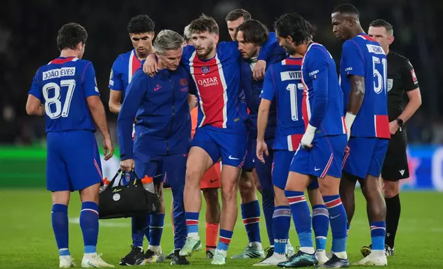 PSG's Khvicha Kvaratskhelia, center, is helped off the field by team staff after sustaining an injury during the Champions League opening phase soccer match between Paris Saint-Germain and FC Barcelona in Paris, Tuesday, Oct. 20, 2026. (AP Photo/Thibault Camus)