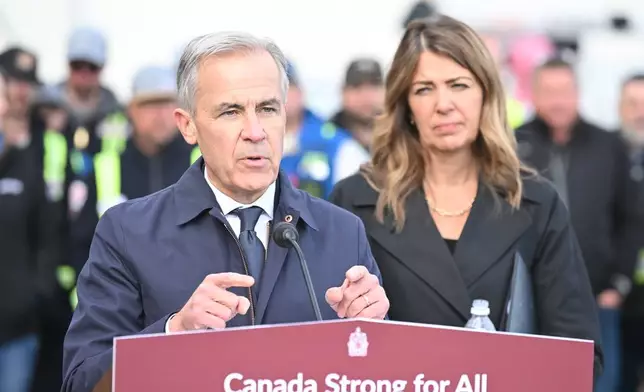 Prime Minister Mark Carney speaks as Alberta Premier Danielle Smith listens during a news conference in Fort McMurray, Alberta, Canada, on Thursday, Oct. 1, 2026, regarding the Pacific Link pipeline project. (Greg Halinda/The Canadian Press via AP)