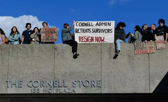 Attendees hold signs during a protest against Cornell University's handling of the 2024 fraternity-house gang rape allegations at the university Monday, Oct. 5, 2026, in Ithaca, N.Y. (AP Photo/Adrian Kraus)