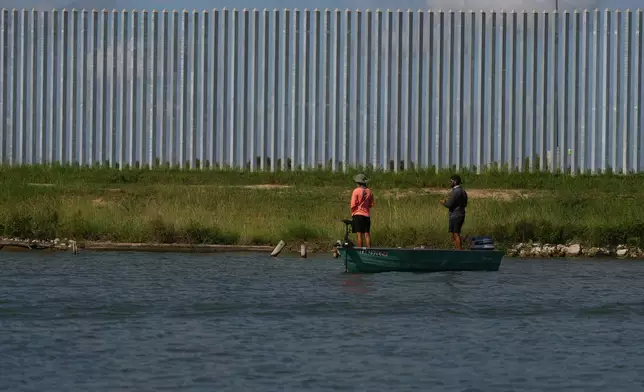 People fish on the Rio Grande new a border wall at the U.S.-Mexico border in McAllen, Texas, Thursday, Oct. 8, 2026. (AP Photo/Eric Gay)