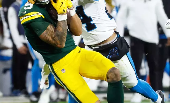 Green Bay Packers wide receiver Christian Watson (9) catches a pass as Carolina Panthers cornerback Will Lee III (24) defends, both are injured on the play, during the first half of an NFL football game in Green Bay, Wis., Thursday, Oct. 29, 2026. (AP Photo/Mike Roemer)