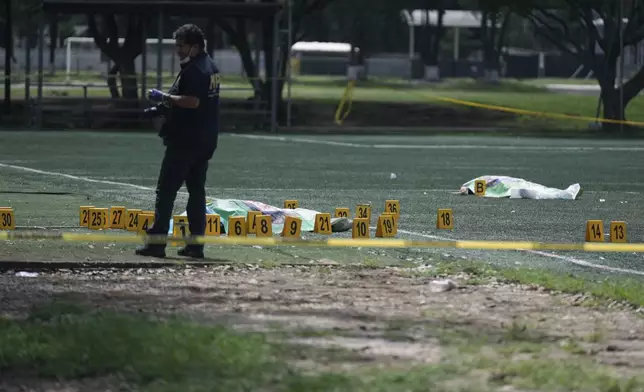 A Public Ministry investigator collects evidence near the body of Juan Francisco Solorzano Foppa, a former anti-gang prosecutor and superintendent of the Tax Administration, at a soccer field following a shooting in Guatemala City, Saturday, Oct. 17, 2026. (AP Photo/Emmanuel Andres)