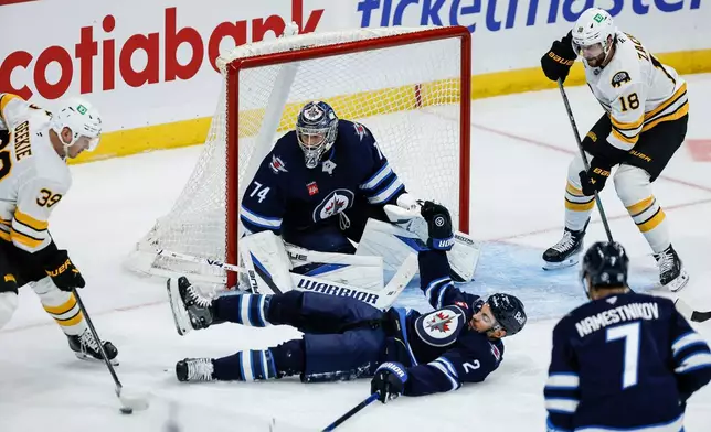 Winnipeg Jets' Dylan DeMelo (2) goes down to block a pass by Boston Bruins' Morgan Geekie (39) to Bruins' Pavel Zacha (18) during the second period of an NHL hockey game in Winnipeg, Manitoba, Friday, Oct. 2, 2026. (John Woods/The Canadian Press via AP)