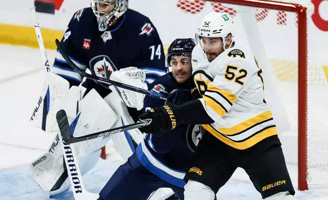 Winnipeg Jets' Dylan DeMelo, center, defends against Boston Bruins' Sean Kuraly (52) in front of Jets goaltender Stuart Skinner (74) during the first period of an NHL hockey game in Winnipeg, Manitoba, Friday, Oct. 2, 2026. (John Woods/The Canadian Press via AP)