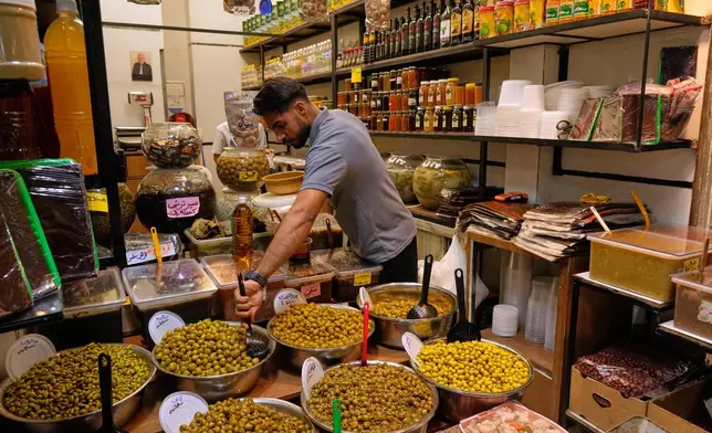 A shopkeeper arranges olives at his shop at Tajrish traditional bazaar in Tehran, Iran, Thursday, Oct. 22, 2026. (AP Photo/Vahid Salemi)