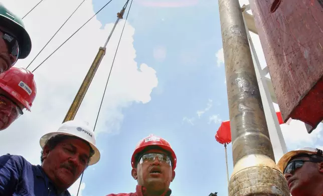 FILE - Venezuela's President Hugo Chavez visits oil workers on the platform of an oil drill in the Orinoco Belt in Venezuela's Anzoategui state, Aug. 10, 2006. (AP Photo/File)