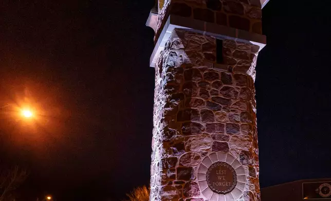 A group of young men pay their respects to the victims of a grass fire that killed four soldiers at Canadian Forces Base Wainwright, at the Memorial Clock Tower in Wainwright, Alberta, on Sunday, Oct. 18, 2026. (John Ulan/The Canadian Press via AP)