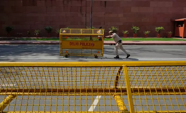 A police officer sets up a barricade around Parliament ahead of a protest organized by opposition parties in New Delhi, India, Tuesday, Oct. 6, 2026. (AP Photo/Manish Swarup)