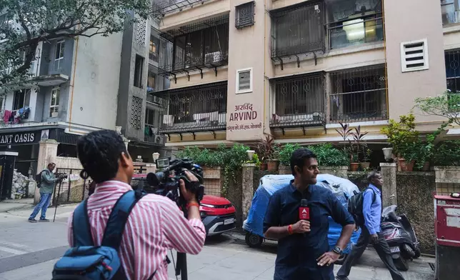 News media personnel stand outside the building where relatives of Smit Machchhar, an Indian pilot for Flydubai, previously lived in Mumbai, India, Thursday, Oct. 1, 2026. (AP Photo/Rafiq Maqbool)