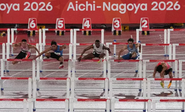 Japan's Shunsuke Izumiya, right, falls over a hurdle in a heat of the men's 110-meter hurdles at the Asian Games in Nagoya, Japan, Saturday, Sept. 26, 2026. (AP Photo/Eugene Hoshiko)