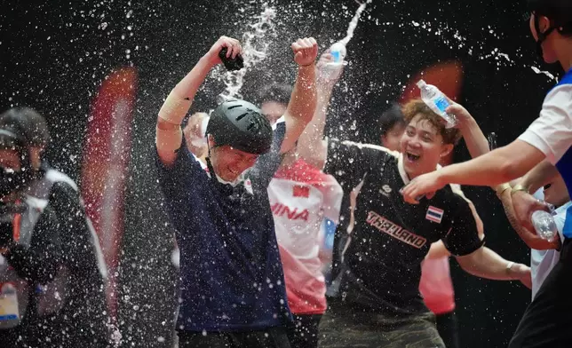 Japan's Rimu Nakamura, left, reacts as other athletes douse him with water after winning the men's cycling BMX freestyle final at the Asian Games in Nagoya, Japan, Sunday, Sept. 27, 2026. (AP Photo/Aaron Favila)