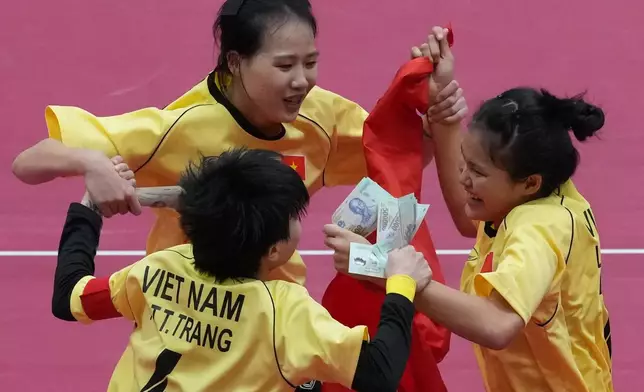 Vietnam's team holds cash and their flag as they celebrate their win against the Philippines' in the sepaktakraw women's doubles final at the Asian Games in Nagoya, Japan, Tuesday, Sept. 29, 2026. (AP Photo/Mark Baker)