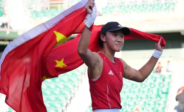 China's Wang Xiyu carries a flag as she celebrates her win over China's Zhang Shuai during the Women's singles final tennis match at the Asian Games in Nagoya, Japan, Friday, Oct. 2, 2026. (AP Photo/Aaron Favila)