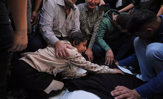 Dima Yassin mourns over the body of her mother, Dina Yassin, during the funeral of her parents, who were killed in an Israeli army strike on an apartment in Gaza City, Tuesday, Oct. 20, 2026. (AP Photo/Jehad Alshrafi)