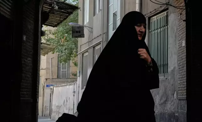 A woman pulls a trolley while walking at an old neighbourhood in southern Tehran, Iran, Thursday, Oct. 1, 2026. (AP Photo/Vahid Salemi)