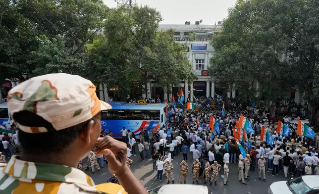 A security person keeps vigil from the rooftop of a building as members of the student wing of India's Congress party and other protesters gather to start a march demanding the resignation of the country's election chief Gyanesh Kumar, in New Delhi, India, Thursday, Oct. 8, 2026. (AP Photo/Manish Swarup)