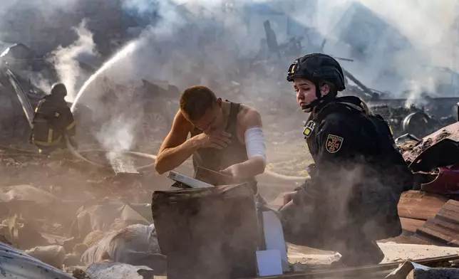 An injured man collects his personal belongings in front of his house destroyed in a Russian strike on Kharkiv, Ukraine, Sunday, Oct. 11, 2026. (AP Photo/Andrii Marienko)