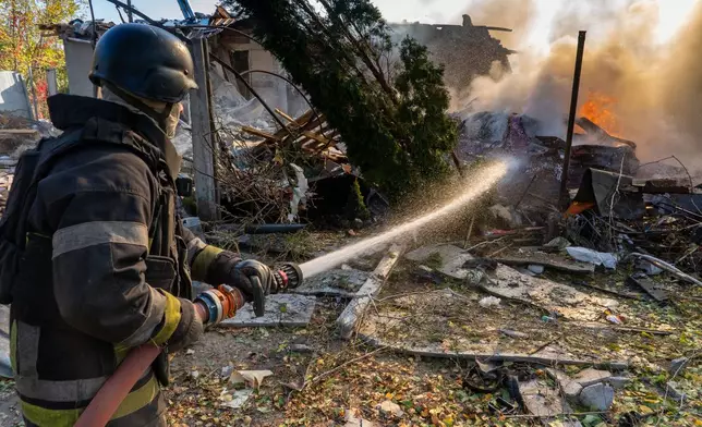 A rescue worker puts out a fire at residential houses destroyed in a Russian strike on Kharkiv, Ukraine, Sunday, Oct. 11, 2026. (AP Photo/Andrii Marienko)