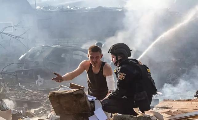 An injured man collects his personal belongings in front of his house destroyed in a Russian strike on Kharkiv, Ukraine, Sunday, Oct. 11, 2026. (AP Photo/Andrii Marienko)