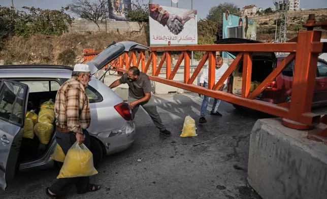 Palestinians transport bags of semolina past a military gate closed to vehicles during an Israeli army operation in Hebron, in the occupied West Bank, Saturday, Oct. 24, 2026, a day after a Palestinian shooting attack in the area. (AP Photo/Mahmoud Illean)