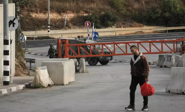 Palestinians cross on foot past a military gate closed to vehicles during an Israeli army operation in Hebron in the occupied West Bank Saturday, Oct. 24, 2026, a day after a Palestinian shooting attack in the area. (AP Photo/Mahmoud Illean)