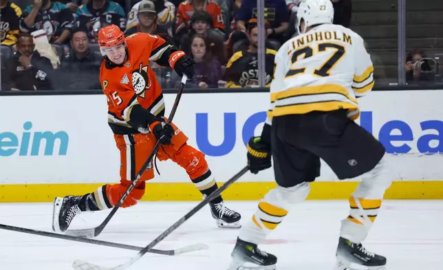 Anaheim Ducks right wing Beckett Sennecke, left, shoots against Boston Bruins defenseman Hampus Lindholm during the second period of an NHL hockey game Friday, Oct. 16, 2026 in Anaheim, Calif. (AP Photo/Ryan Sun)
