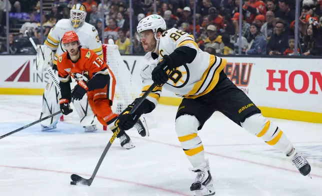 Boston Bruins right wing David Pastrnak, right, moves the puck ahead of Anaheim Ducks center Nikita Nesterenko (13) during the second period of an NHL hockey game Friday, Oct. 16, 2026, in Anaheim, Calif. (AP Photo/Ryan Sun)