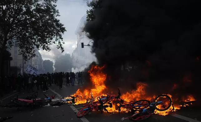 Bicycles burn during a demonstration against rising living costs, joining students' grievances, in Paris, Saturday, Oct. 17, 2026. (AP Photo/Thibault Camus)