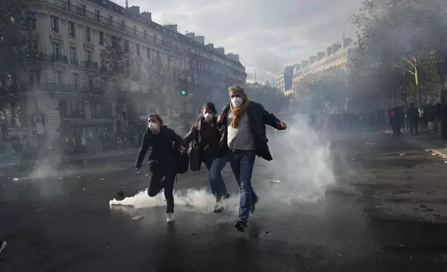 Protesters run to leave the Republique square during a demonstration against rising living costs, joining students' grievances, in Paris, Saturday, Oct. 17, 2026. (AP Photo/Thibault Camus)