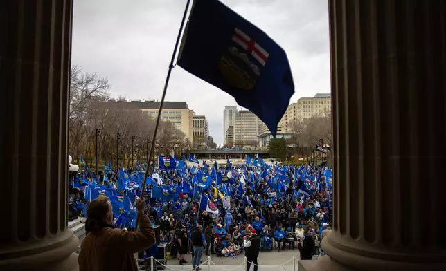 An attendee waves the Alberta flag at the crowd during an Alberta independence rally at the Alberta legislature in Edmonton Alberta, Saturday, Oct. 17, 2026. (Amanda May Erickson/The Canadian Press via AP)