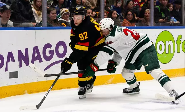 Minnesota Wild's Matt Kiersted, right, checks Vancouver Canucks' Liam Ohgren (92) during the first period of an NHL hockey game, in Vancouver, British Columbia, Sunday, Oct. 25, 2026. (Jacob Mallari/The Canadian Press via AP)