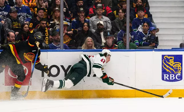 Vancouver Canucks' Max Sasson, left, hits Minnesota Wild's Quinn Hughes (43) during the first period of an NHL hockey game, in Vancouver, British Columbia, Sunday, Oct. 25, 2026. (Jacob Mallari/The Canadian Press via AP)