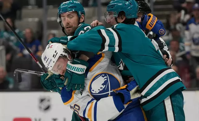 Buffalo Sabres center Noah Östlund, bottom, is grabbed by San Jose Sharks center Barclay Goodrow, top left,, and defenseman Michael Kesselring during the second period of an NHL hockey game, Tuesday, Oct. 27, 2026, in San Jose, Calif. (AP Photo/Jeff Chiu)