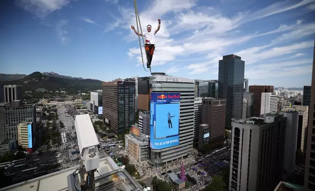 Estonian slackliner Jaan Roose performs on a slackline during South Korea's first urban highline crossing event which is on a 160-meter-long and suspended 120 meters above the ground, in central Seoul, South Korea, Thursday, Oct. 1, 2026. (Kim Hong-Ji/Pool Photo via AP)