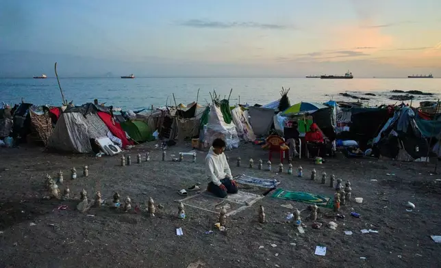 A migrant prays during the morning on El Trampolín Beach in the Spanish enclave of Ceuta Thursday, Oct. 1, 2026. (AP Photo/Bernat Armangue)