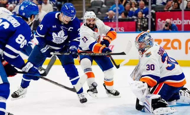 New York Islanders goaltender Ilya Sorokin (30) makes a save as Toronto Maple Leafs' Auston Matthews (34) and Islanders' Kyle Palmieri (21) battle for the rebound during the second period of an NHL hockey game in Toronto, Wednesday, Sept. 30, 2026. (Frank Gunn/The Canadian Press via AP)