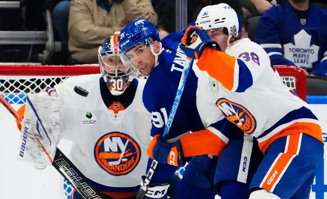 New York Islanders goaltender Ilya Sorokin (30) watches the puck as Toronto Maple Leafs' John Tavares (91) battles with Victor Eklund (38) during the first period of an NHL hockey game in Toronto, Wednesday, Sept. 30, 2026. (Frank Gunn/The Canadian Press via AP)