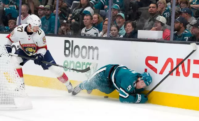 San Jose Sharks defenseman Nolan Allan (5) is checked into the boards by Florida Panthers center Eetu Luostarinen (27) during the second period of an NHL hockey game in San Jose, Calif., Thursday, Oct. 1, 2026. (AP Photo/Tony Avelar)