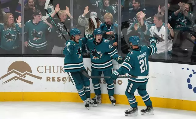 San Jose Sharks defenseman Luca Cagnoni (42) celebrates with Will Smith (2) and Alexander Wennberg (21) after scoring in a overtime against the Florida Panthers in a NHL hockey game in San Jose, Calif., Thursday, Oct. 1, 2026. (AP Photo/Tony Avelar)